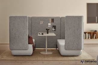 Akoestische belcel met grijze wollen wanden, wit zitgedeelte, ronde tafel en twee stoelen in moderne kantooromgeving.
