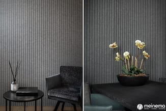 Moderne inrichting met verticale grijze wandafwerking, zwarte ronde tafel met diffuser, zwarte stoel, en bloemenarrangement i