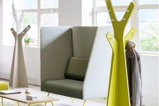 Modern kantoorinterieur met grijsgroene fauteuil, gele garderobe in Y-vorm, witte kapstok en hoge ramen.