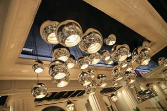 Hangende glazen pendellampen in goudkleur met warmwit licht, meerdere stuks aan plafond gemonteerd in moderne kantoorruimte.