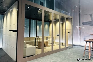 Glazen belcel met taupe aluminium frame in modern kantoor, voorzien van witte binnenwanden, houtkleurige stoel en groene plan