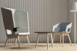 Lounge-opstelling met grijze highback-fauteuil, blauwe stoel en zwart tafeltje op houten vloer tegen verticale wandbekleding.