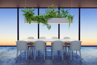 Modern vergaderruimte met grijze stoelen, lichte tafel en hangende plantenbak boven, uitzicht op zee.
