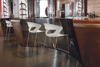 Zwarte design vergadertafel met witte moderne barkrukken met metalen poten in hedendaagse kantooromgeving.