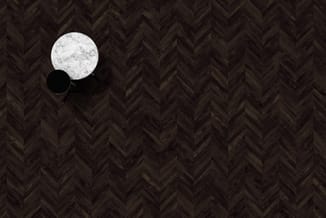 Twee ronde hangende lampen met marmer- en zwart oppervlak boven herringbone patroon houten vloer.