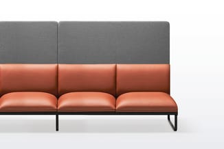 Moderne bank met drie zitplaatsen, combinatie van cognackleurig leer en grijze stof, zwart metalen frame, tegen witte achterg