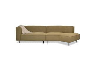 Grijsgroene hoekbank met chaise longue-zitgedeelte, zwarte poten en beige plaid op de armleun.