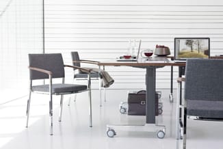 Modern kantoor met verstelbare tafel op wielen, grijze stof stoelen met houten armleuningen, laptop, decoratie en raam op ach