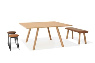 Houten vergadertafel met vier houten poten, twee houten bankjes en twee krukjes met bruin leren zit en zwart metalen frame.