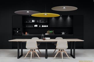 Moderne keuken met zwarte kastenwand, houten tafel op zwarte poten, twee witte stoelen met houten poten, en drie hangende pla