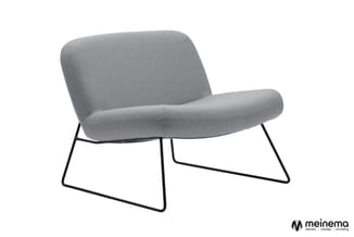 Grijze loungestoel met afgeronde vormen en zwart stalen frame op wit oppervlak.