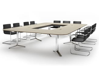 U-vormige vergadertafel in licht hout met chrome onderstel, omringd door zwarte kantoorstolen met chroom frame op witte achte