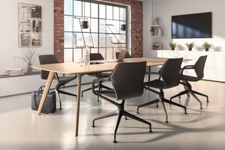 Moderne vergaderruimte met houten tafel, vier zwarte bureaustoelen met wielbasis, groot raam met bakstenen frame, tv aan wand