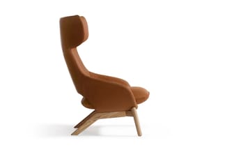 Bruine lederen fauteuil met hoge rugsteun en hoofdsteun, houten spreidpoten, zijkant tegen witte achtergrond.