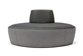Ronde grijze loungebank met donkergrijs gestoffeerde rugleuning, minimalistisch design op witte achtergrond.