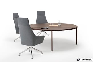 Ronde tafel in donker hout met zwart onderstel, omringd door drie grijze stoelen met metalen poten. Op tafel een smartphone e