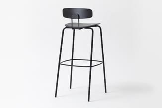 Zwarte barkruk met ronde zitting, gebogen rugleuning en metalen frame met voetsteun, tegen witte achtergrond.