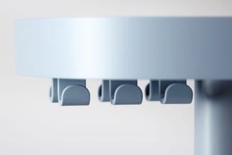 Witte akoestische hangende panelen met drie blauwe semi-cilindervormige geluiddempers eronder tegen lichte achtergrond.