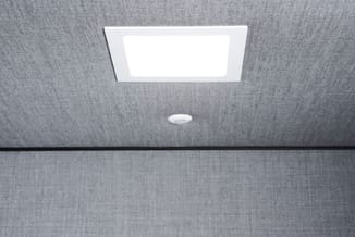 Plafond met grijze akoestische tegels, rechthoekige LED-paneel en kleine ronde inbouwspot.