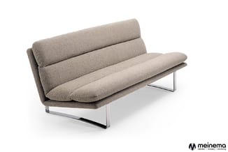 Grijsbeige designbank met opvouwbare rugkussens, chromen onderstel, schuin geplaatst tegen witte achtergrond.