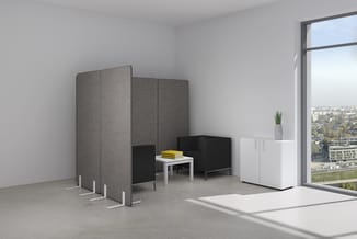 Akoestische wanden in grijs, zwart zitmeubel met tafel, witte kast en plant in modern kantoorinterieur met raampartij.