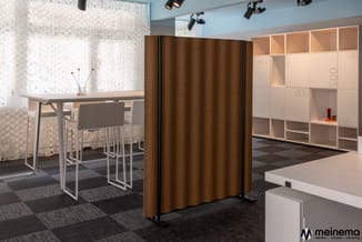 Moderne kantoorruimte met bruine stoffenscherm, houten bureau met zwarte barkrukken, lichte houten kasten met vakken en witte