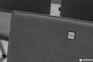 Grijze stofbekleding met label "123" in een showroom of kantooromgeving.
