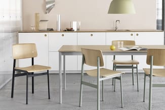 Moderne eetkamer met houten tafel, stoelen met licht houten zitting en zwart/grijs frame, witte keukenkasten op achtergrond e
