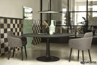 Zwarte ronde vergadertafel met twee grijze stoelen in moderne kantoorruimte met zwart-wit tegelmotief en glazen wanden.