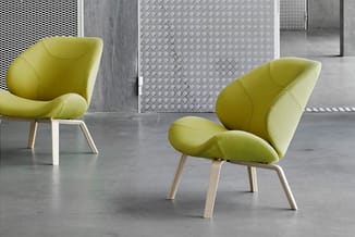 Twee gele organisch gevormde fauteuils met houten poten in een moderne kantoorruimte met betonnen vloer en grijze wanden.