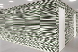 Wand bekleed met groen-wit gestreepte akoestische panelen in moderne kantoorruimte met recessed verlichting.