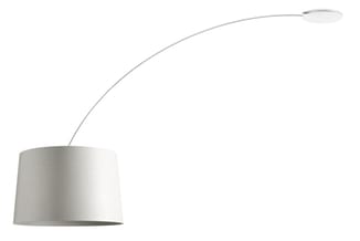 Boogvloerlamp met witte/grijze lampenkap en gebogen arm, hangend boven de grond.