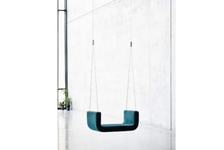 Hangend akoestisch meubel in blauwtinten met U-vorm, opgehangen aan twee zilveren kabels in minimalistisch wit interieur.