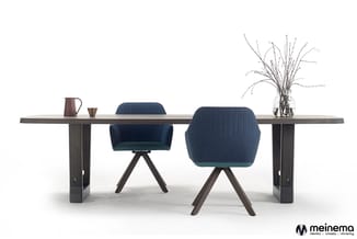 Donkerhouten vergadertafel met twee blauwe draaistoelen met armleuningen, bruin kannetje, goudkleurig object en glazen vaas m