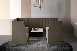 Twee beige akoestische boxen met zitplaatsen rond een wit vierkant tafeltje met laptop, onder hangende designverlichting in m