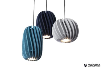 Drie hangende kogelvormige pendels in blauw, donkerblauw en grijs met verticale lamellen en verlichte onderkant tegen witte a