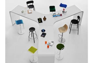 Kantoormeubelen arrangement: wit hoekbureau met zwarte en blauwe stoelen, verstelbare barkrukken, groene en gele zitondersteu