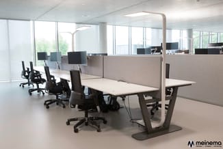 Modern open kantoor met witte werkafels, beige akoestische scheidingswanden, zwarte ergonomische stoelen en monitor-armen ond