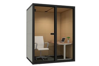 Zwarte modulaire belcel met glazen deuren, beige akoestische wanden, witte bureaustoel, houten bureau met laptop en plantje.