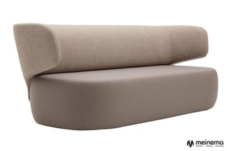 Moderne bank met gebogen vormen, grijs-beige bekleding, cilindervormige rugkussen, zitgedeelte met afgeronde vormen.