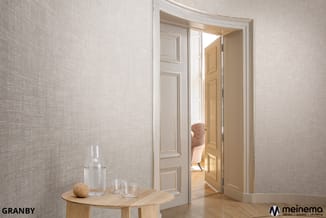 Moderne kantoorruimte met beige geweven wand, houten bijzettafel met glas water en kurk decoratie, openslaande deur naar aang