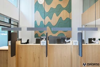 Modern kantoor met houten receptiebalie, blauwe akoestische schermen, genummerde loketten (04, 05) en golvend muursculptuur i