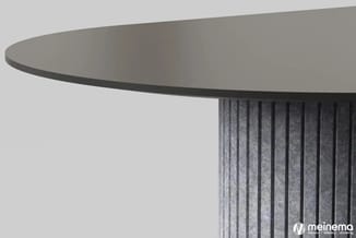 Ronde tafel met grijs blad en gegroefde grijze zuilvormige ondersteuning tegen lichte achtergrond.