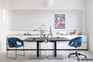 Modern kantoor met zwart bureau, twee blauwe stoelen, witte kastenwand met beeldscherm en poster "Smedkernes Efterårsudstiili