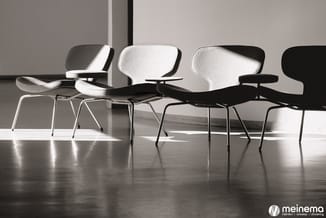 Vier moderne stoelen met witte en zwarte bekleding en metalen poten, gerangschikt in een lichte kantoorruimte met glanzende v