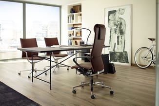 Modern kantoor met zwartmetalen bureau, bruine draaistoel met hoofdsteun, twee bezoekersstoelen, open boekenkast en grote ram
