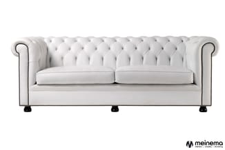 Witte Chesterfield-bank met kapitonnering, twee zitplaatsen, zwarte poten en nailhead-afwerking.