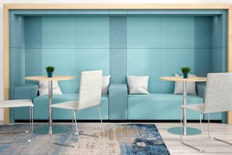 Moderne lounge met turquoise geluidsabsorberend paneel, lichte stoelen aan ronde houten tafels, kussens en potplanten.