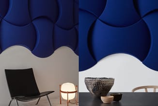Moderne kantoorinrichting met zwarte design stoel, ronde lamp met houten frame, textiele wandpanelen in blauw, en decoratieve