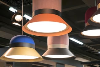 Hangende LED-pendellampen in oranje, geel en zwart met witte lichtschijven in moderne kantoorruimte.